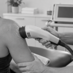 Practitioner applies a SoftWave therapy device to a patient's shoulder